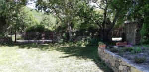 einen Garten mit einem Zaun und einer Steinmauer in der Unterkunft Casa San Salvadore in Favalello