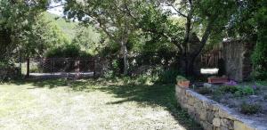 un jardín con una valla y una pared de piedra en Casa San Salvadore en Favalello