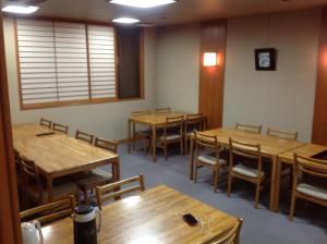 una sala da pranzo con tavoli e sedie in legno di Nakayasu Ryokan a Kanazawa Altre 25 foto