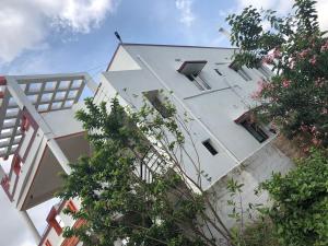 um edifício branco alto com janelas e árvores em Castle 50 em Coimbatore