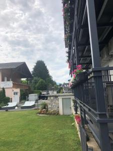 a yard with a house with flowers and a fence at Enjoyit Rooms in Velden am Wörthersee