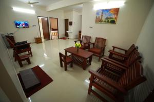 una sala de estar con sillas de madera y una mesa con flores. en Indeevaram Residency en Thiruvananthapuram