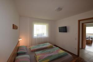 a bedroom with two beds and a television on the wall at Garnhof in Coldrano