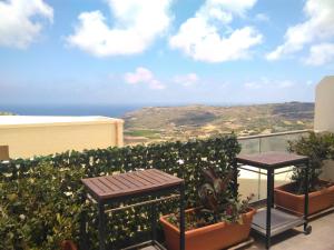 a balcony with two tables and a view of the ocean at R1100ERI Ramla Bay by euroresort in Xagħra