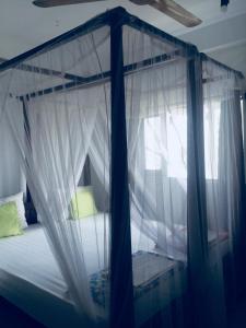 Schlafzimmer mit Himmelbett und weißen Vorhängen in der Unterkunft Fort Inn Guest House in Galle