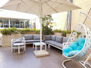 een patio met een bank, stoelen en een parasol bij Harmony Hotel - an Atlas Boutique Hotel in Jeruzalem