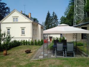 einen Tisch und Stühle mit einem Regenschirm und einem Haus in der Unterkunft Fewo am Personenaufzug in Bad Schandau