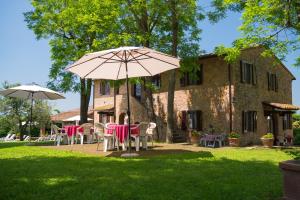 a table and chairs with an umbrella in front of a house at Pian della Casa in Montaione