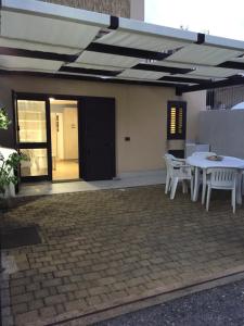 d'une terrasse avec des tables et des chaises blanches et une porte noire. dans l'établissement Casamare Lido di Noto, à Noto Marina