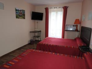 een hotelkamer met 2 bedden en een televisie bij Logis Hôtel Restaurant de la Poste in Tarascon-sur-Ariège