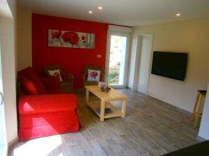 a living room with a red couch and a table at Les Jardins de Soulane B&B - Adults only in Belcastel-et-Buc