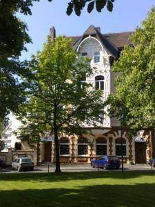 une grande maison avec des voitures garées devant elle dans l'établissement Hotel Antoni, à Bochum