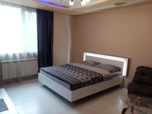 1 dormitorio con 1 cama y 1 silla en Uzh Apartments, en Uzhhorod