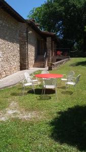 een rode tafel en stoelen in het gras bij Casa Trastullo in Massa Martana