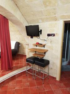 Habitación con 2 taburetes y TV en la pared en Casa Vacanze IL SEDILE en Oria