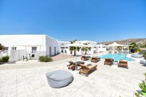 a patio with a pool and chairs and a swimming pool at Queen Boutique Suites in Mikonos