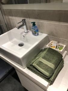 un lavandino in bagno con asciugamano verde e una bottiglia di sapone di Venetian Aesthetic Apartment a Mestre