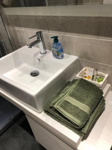 un lavabo con una toalla verde y una botella de jabón en Venetian Aesthetic Apartment, en Mestre