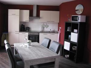 uma cozinha com uma mesa de madeira e cadeiras num quarto em Schlummerkasten em Sievern