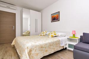 a white bedroom with a bed and a chair at Pink in Tučepi