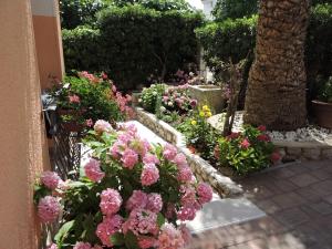 a garden filled with pink flowers in front of a building at Neda Apartmani in Mali Lošinj