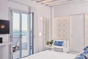 a white bedroom with a view of the ocean at Katikies Mykonos - The Leading Hotels of the World in Agios Ioannis Mykonos