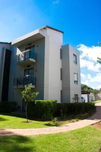 une maison blanche avec un arbre devant dans l'établissement Luxury 2 Bedroom Lifestyle Apartment in Golf Estate, à Roodepoort