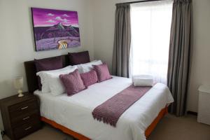 - une chambre avec un lit doté d'oreillers violets et d'une fenêtre dans l'établissement Luxury 2 Bedroom Lifestyle Apartment in Golf Estate, à Roodepoort 39 autres photos