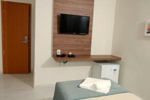 a room with a television on a wall with a bed at Asa Branca Hotel in Araripina