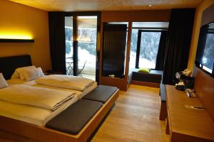 1 dormitorio con 2 camas y TV. en Gradonna Mountain Resort Chalets & Hotel en Kals am Großglockner