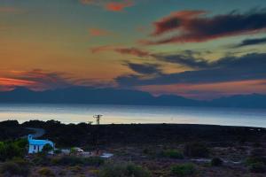 a sunset over the ocean with a house in the foreground at Element Hotel in Elafonisos