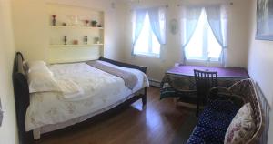 sypialnia z łóżkiem, stołem i oknami w obiekcie Youth Hostel w mieście Charlottetown