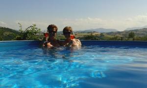 zwei Personen in einem Pool mit Gläsern Wein in der Unterkunft Casa Oleandro in Fratte Rosa in San Lorenzo in Campo
