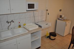 a kitchen with a sink and a microwave and a refrigerator at Gitta Apartmanház in Zalakaros +59 photos