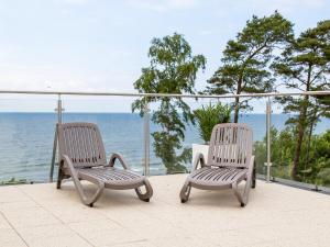 dwa krzesła siedzące na balkonie z widokiem na ocean w obiekcie Apartament Wiatr i Woda z basenem w Rewalu