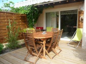 une table et des chaises en bois sur une terrasse en bois dans l'établissement Villa Le Mauret, à Andernos-les-Bains