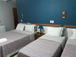 a bedroom with two beds and a blue wall at Hotel Pousada Oasis Park in Jaboticabal