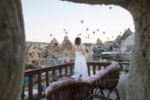 kobieta stojąca na balkonie patrząca na miasto w obiekcie Mia Cappadocia Cave Hotel w Göreme