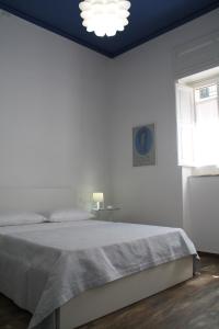 a white bedroom with a bed and a window at Le Logge in Scicli