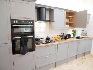 a kitchen with white cabinets and a stove top oven at The Gill Gardens Barn - Private Hot Tub Ulverston - Lake District in Ulverston
