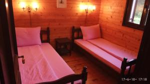 two beds in a wooden room with pink sheets at Apartments Vila Marija in Žabljak