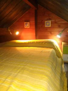 a bed in a wooden room with a yellow comforter at El mirador del consuelo in Jorquera