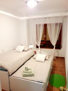two beds in a white room with a window at Apartamento Villananitos in San Pedro del Pinatar