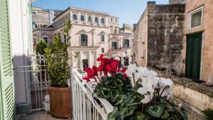 a balcony with red and white flowers on a building at L'Incanto Luxury Rooms in Matera