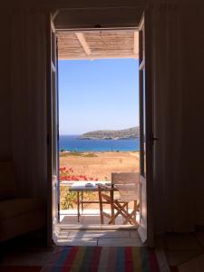 uma porta aberta com uma mesa e vista para o oceano em Island White em Agios Georgios