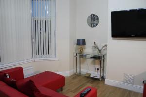Van Apartments في كيرفيلي: غرفة معيشة مع أريكة حمراء وتلفزيون بشاشة مسطحة