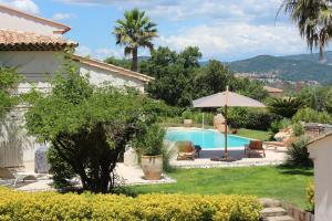 a garden with a swimming pool and a house at Villa Le B in Cogolin