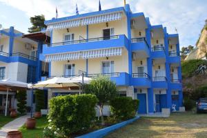 a blue and white building with umbrellas in front of it at Kangaroo Hotel in Mola Kalyva