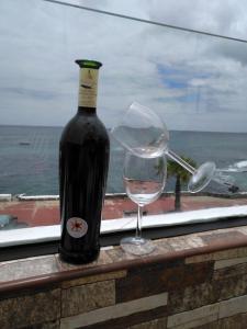 een fles wijn en een wijnglas op een richel bij Casa Corina. Primera línea de mar in Punta de Mujeres