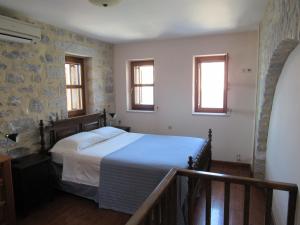 a bedroom with a bed and two windows at Kyrimi in Gerolimenas